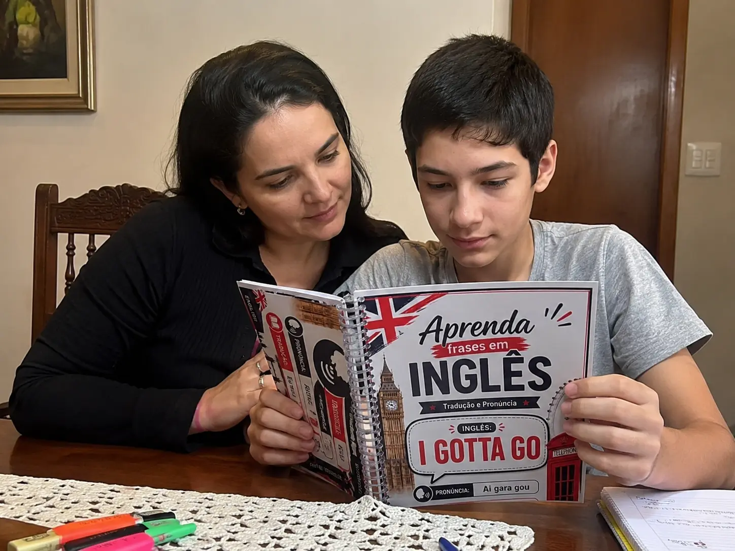 Mãe e filho estudando com a apostila em casa